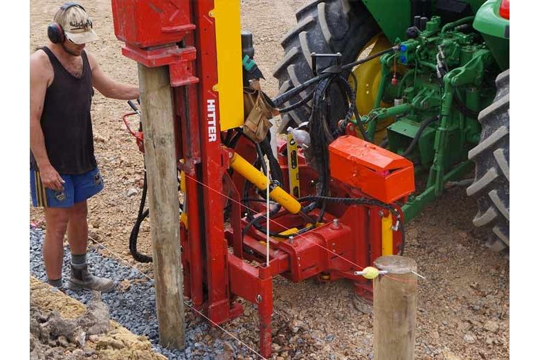 Fencer operating post driver behind tractor