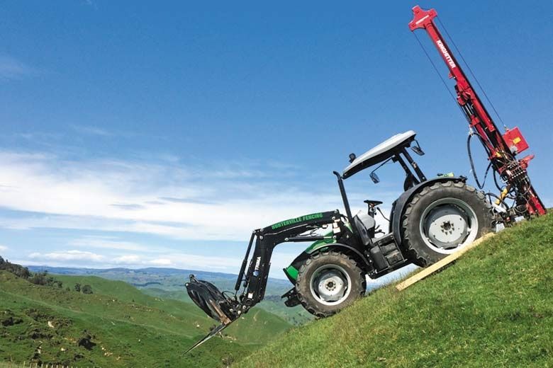 4WD Duetz Fahr tractor on steep hill Kinghitter postdriver ramming posts in fence line